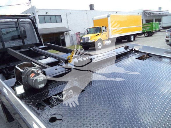 Hino 258ALP truck bed with winch and flat diamond plate surface, visible in foreground; yellow and orange box truck in background.
