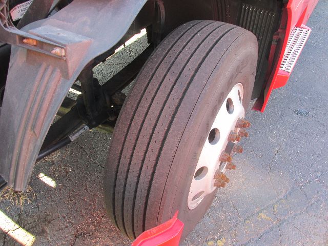 Truck front wheel with five-bolt hub and dual rear dual tires. Visible are large front tire, wheel, and fender; some rust on lug nuts.