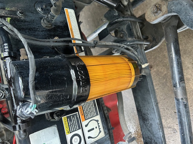 Peterbilt 579 truck engine bay with an orange Donaldson-style filter canister and surrounding labels.