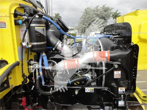 Peterbilt 337 engine bay showing yellow body with blue hoses, black radiator, and various fluid reservoirs.