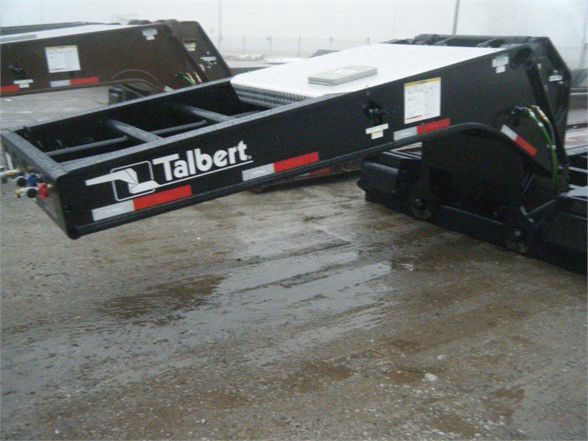 Talbert lowboy trailer with 'Talbert' logo on side, showing flat level deck and hydraulic components. Text visible: Talbert branding along side of the black trailer.