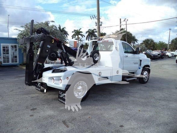 2023 Chevrolet Silverado 6500HD tow truck in white with heavy-duty hooklift arm and wheel lift system, side view.
