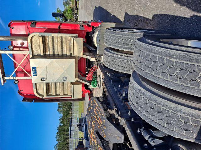 Rear view of a red Freightliner Cascadia truck tractor showing fifth wheel and dual rear axles, with a large aluminum cab fairing and exposed air system piping.