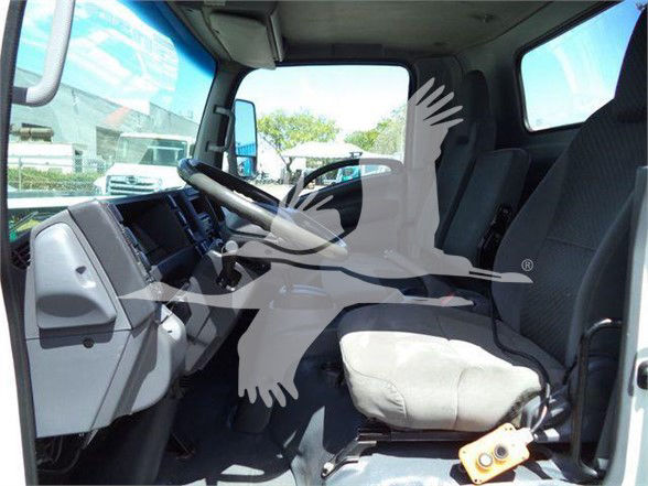 Isuzu NRR truck cabin interior with steering wheel, dashboard, and grey fabric seat. Visible window and side mirror, no visible gauges text.