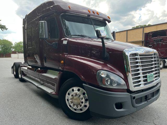 Truck cab exterior in maroon color with chrome grille, Freightliner badge, and large side mirrors. Sleeper cab with step rails and dual rear wheels.