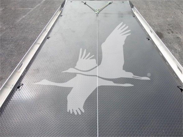 Image of a metallic diamond-plate truck bed with a logo of two flying birds. No visible text other than the trucks platform features.