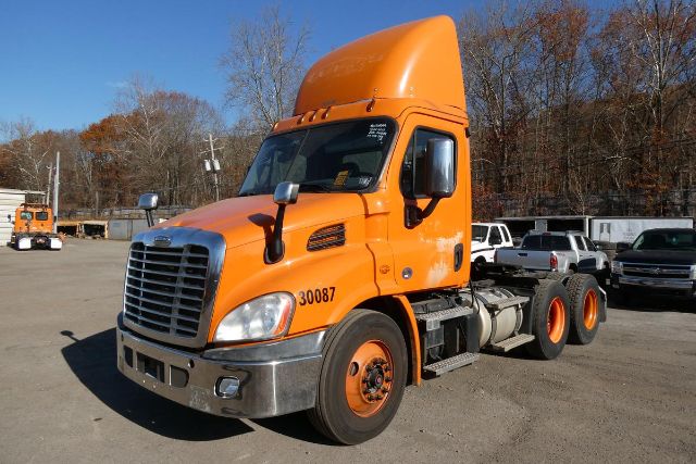 2017 Freightliner Cascadia 113 daycab truck front-left view with orange cab and attached sleeper height, visible grille, headlights, and rear dual axles.