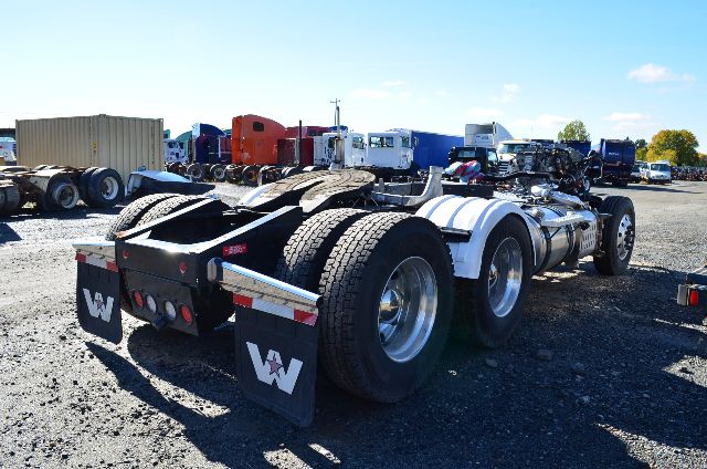 2017 Western Star 5700 XE tractor chassis rear view showing dual rear axles, mudflaps with white star logo, gravel lot with other trucks.