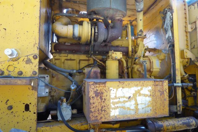 Caterpillar 16G engine bay showing yellow machinery, turbocharger, hoses, and rusted access panel.
