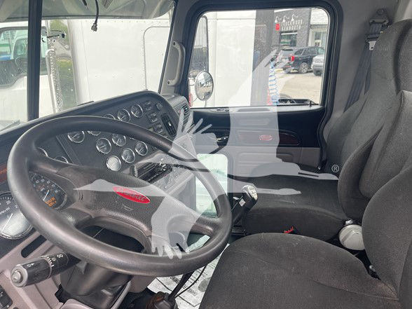 Peterbilt 389 truck cab interior showing steering wheel and dashboard gauges with gray seats