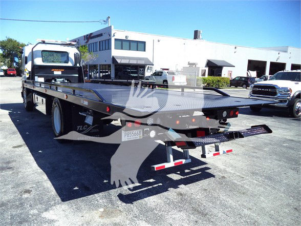 Isuzu FTR flatbed truck with long wheelbase, showing rear of bed, tail lights, and hitch. Visible text includes 'ISUZU' on cab and body, 'FTR' model? and license plate 'P8566E' on rear.