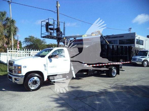 White Chevrolet Silverado 6500HD dump truck with a raised bucket lift on a long chassis, black dump bed, dealership in background.