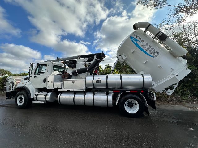 Freightliner M2 vacuum truck with large rear-mounted tank and hose reel, white cab and silver tanks, 2100 printed on tank.