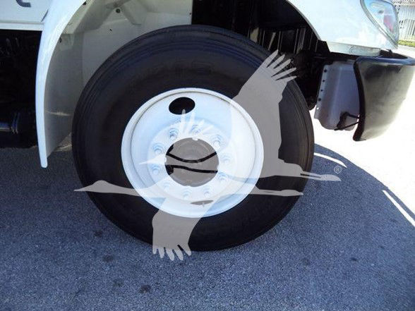 Truck wheel close-up: front tire with white steel wheel on International DURASTAR 4300; visible parts include wheel, fender, and undercarriage; partial hood area.