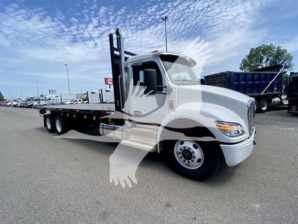 Kenworth T480 flatbed truck in a dealership lot showing a long wheelbase with a flatbed and dual rear axles.