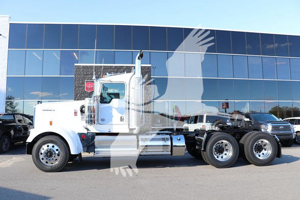 Kenworth W900L conventional daycab truck side view with white cab and dual rear axles in front of a glass building.
