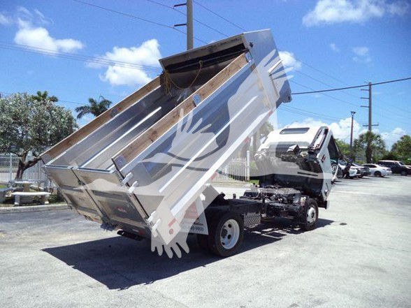 Isuzu NQR dump truck with its bed raised, exposing hydraulic system and rear chassis.