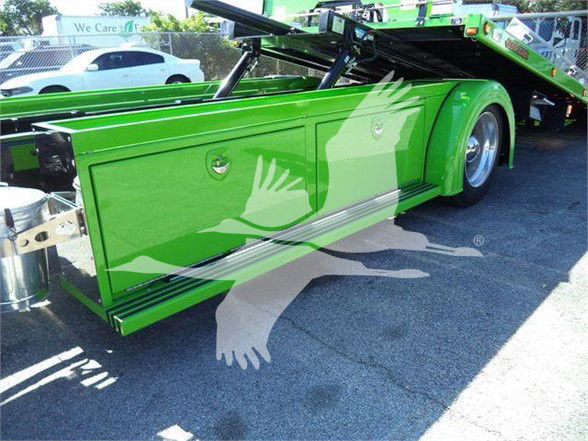 Green Kenworth wheel area with attached tilt bed and metal storage compartments