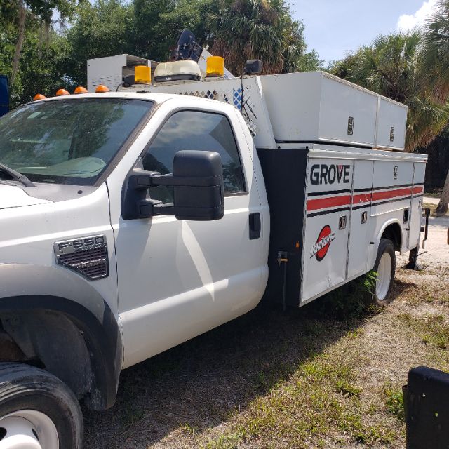 Ford F-550 utility truck with Grove service body and toolboxs in grass, side view showing Hansen line markings.