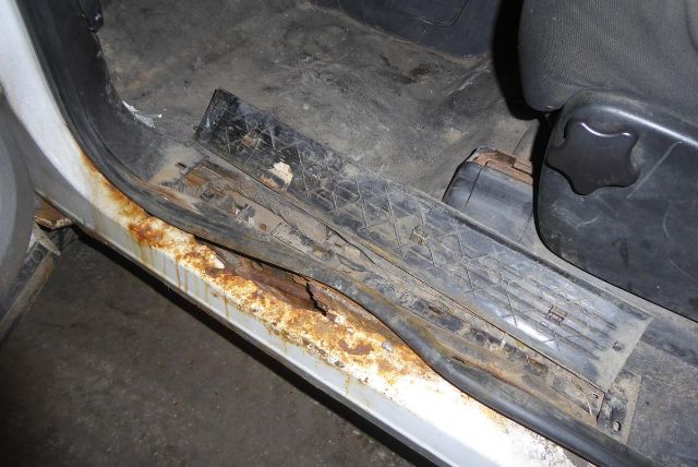 Chevrolet Silverado 2500HD interior entry area with rust on door sill and worn running board, showing floor area near driver seat.
