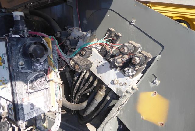 Truck lifting equipment hydraulic manifold with multiple hydraulic hoses and electrical connectors in a Grove T60 boom truck.