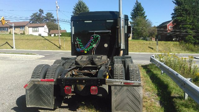 Truck cab rear view showing chassis and fifth wheel connection with dual rear axles and toolboxes.