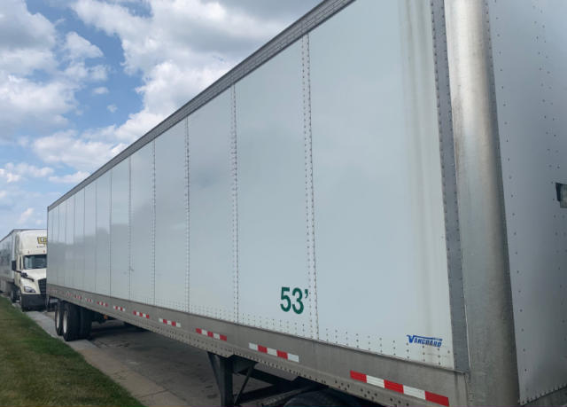 Utility trailer side with green '53'' wheel setup and small blue Vanguard logo near the front.