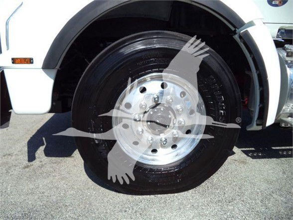 Front wheel of a white Kenworth T880 truck showing a polished steel wheel and tire, with fender and wheel well visible.