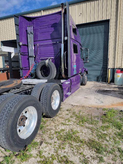 Truck cab rear and side showing a purple Volvo sleeper cab with dual rear axles. Visible text on components includes a coiled air lines and spare wheel.