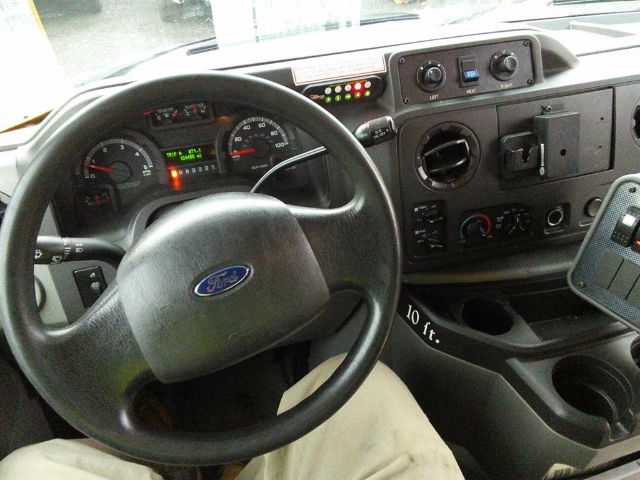 Ford E-450 bus interior showing steering wheel, instrument cluster, and center console with gauges and controls.