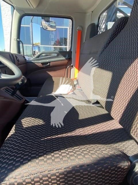 Interior of a 2025 Hino L6 truck cab with plaid seat fabric and steering wheel visible.