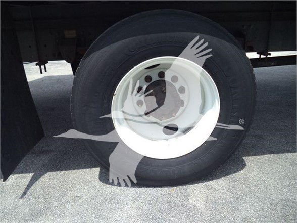 Truck wheel and tire on trailer with white rim; no legible text visible on tire or surrounding.