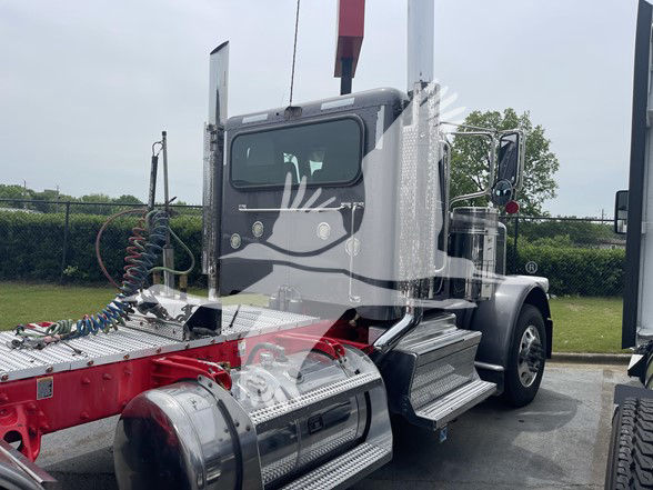 Peterbilt 389 conventional daycab truck chassis visible with chrome fuel tanks, steps, and a red/gray color scheme.