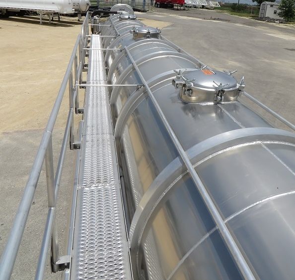 Aluminum vacuum tank trailer top view showing manway access hatch and walkable catwalk with metal railing along cylindrical aluminum tank.