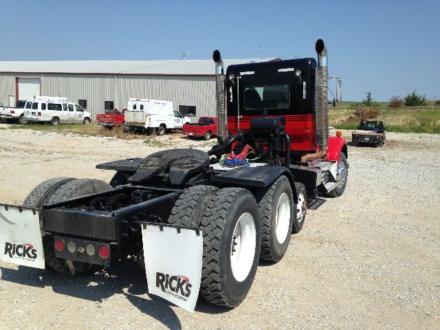 Kenworth T800 tractor rear view showing dual rear axles, mud flaps with 'RICKS' branding, fifth-wheel area, and exhaust stacks.