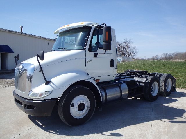 International 8600 conventional daycab truck in white, front-left view, seats and large grille, dual rear axles, fuel tanks, and wheels visible.