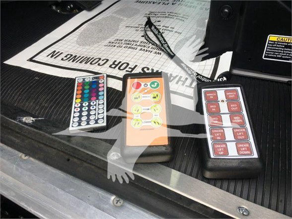 Truck showing three remote control panels with colored buttons on a cargo bed, some papers, and a caution sticker near a Peterbilt truck interior.