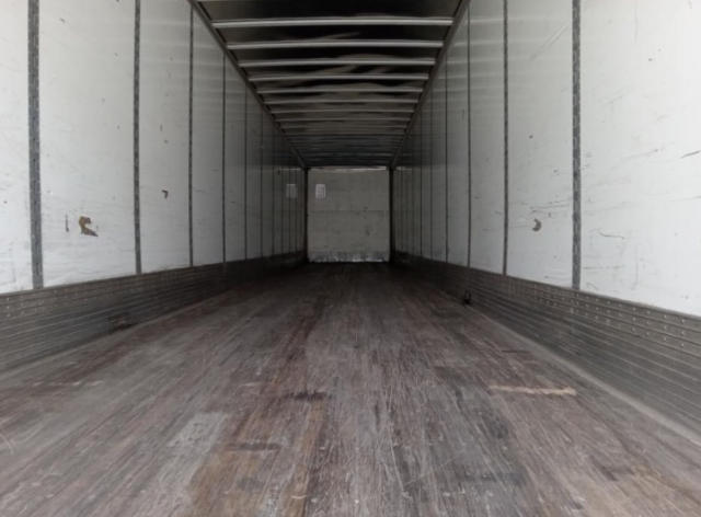 Trailer interior showing empty cargo space with wooden floor and white side walls