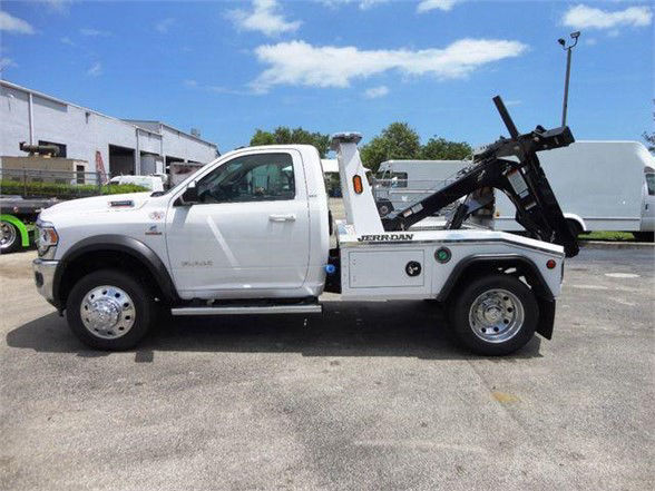 Side view of a white 2024 Ram 4500 tow truck with a front cab and a rear hooklift system labeled Jerr-Dan. Stock number J68869.