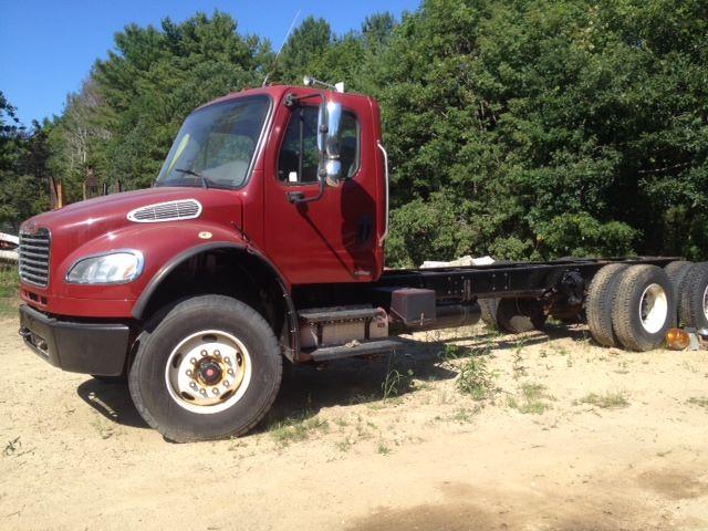 Red Freightliner M2106 cab and chassis truck with dual rear axles and exposed frame