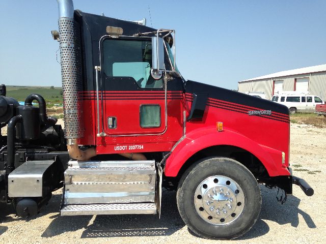 Kenworth T800 side profile showing cab, red and black paint, chrome exhaust stack, and front wheel with large hub.